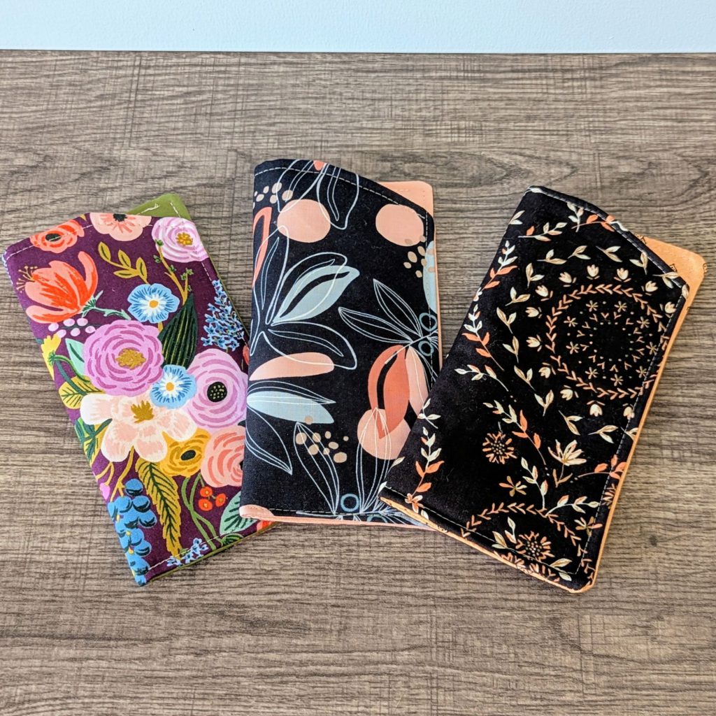 Three eyeglass pouches laying on wooden surface.