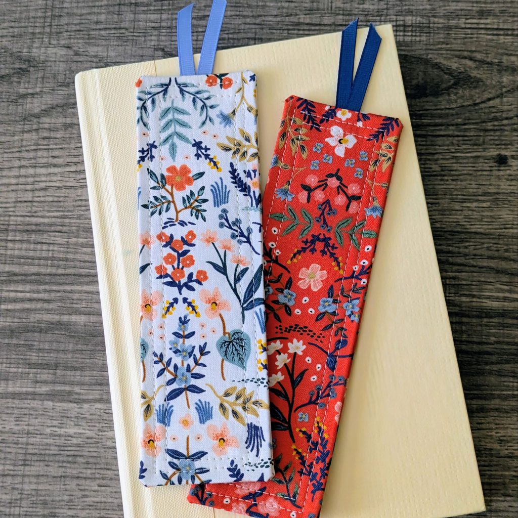 Two floral classic bookmarks laying on a cream hardcover book.