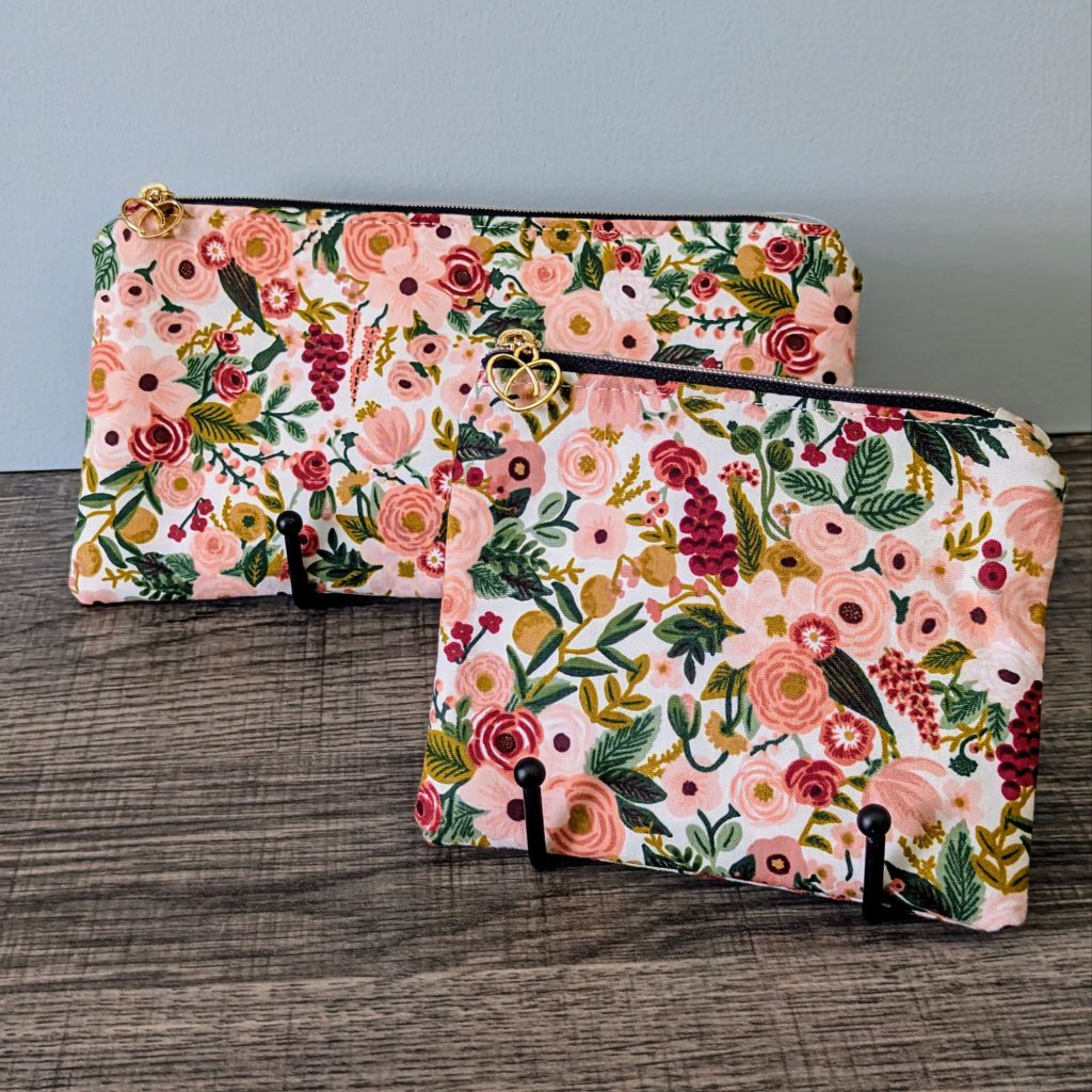 Pink floral cotton zipper pouches in two sizes displayed on table.